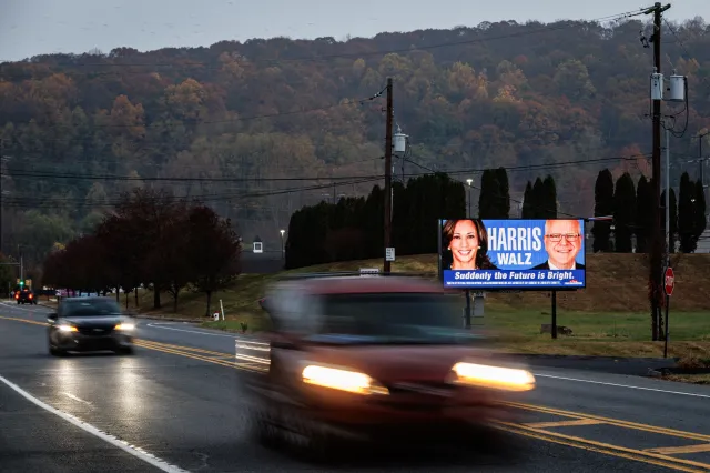Vehicles drive past a campaign ad for Democratic presidential candidate Kamala Harris and running mate Tim Walz in Northampton County, Pennsylvania, on November 5, 2024.