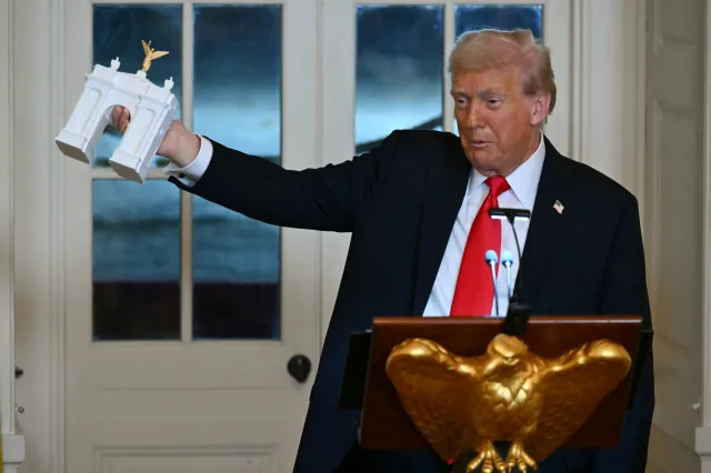 President Donald Trump holds up a model for a proposed Triumphal Arch as he speaks during a dinner at the White House on October 15, 2025.