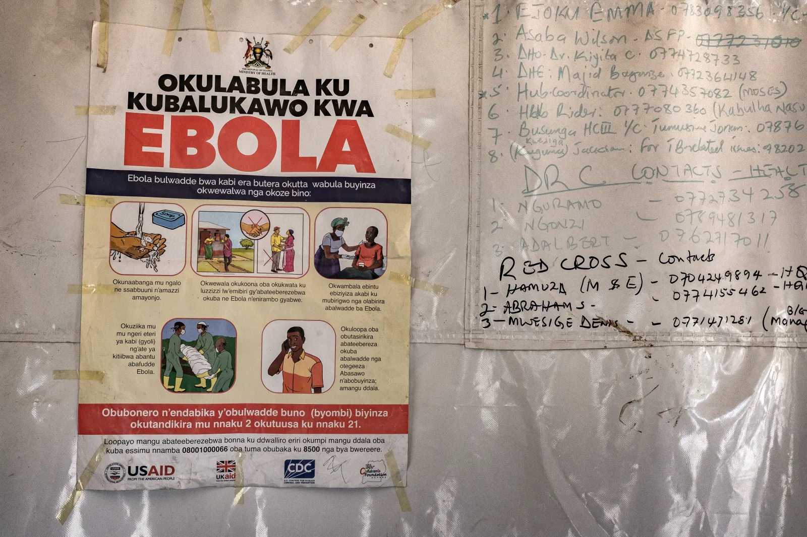 A poster displaying Ebola emergency contact numbers is pinned to a tent at the Busunga border crossing between Uganda and the Democratic Republic of Congo in Bundibugyo, on May 18, 2026. (Photo by Badru Katumba / AFP via Getty Images)