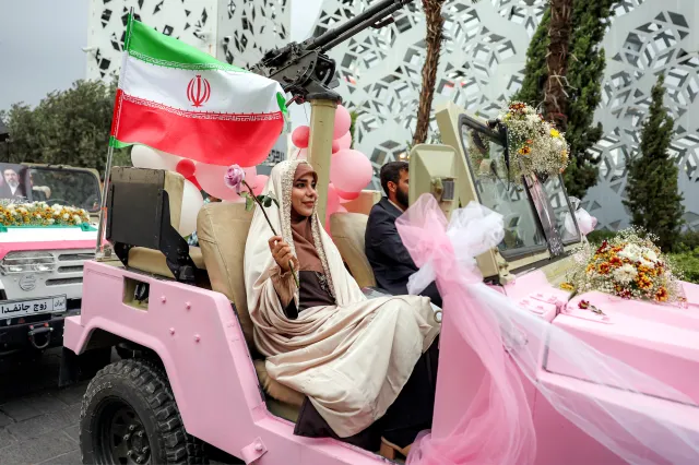 A bride and groom ride in a military jeep arriving for a public mass wedding ceremony at Imam Hossein Square in Tehran on May 18.