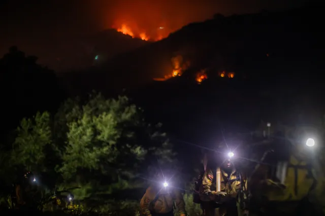 Firefighters walk back to their fire truck as the Sandy Fire continues to burn in the hills of Simi Valley, California, on May 18, 2026.