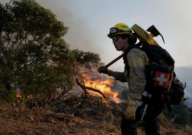 SIMI VALLEY, CALIFORNIA - MAY 18: A Cal Fire firefighter battles the Sandy Fire on May 18, 2026 in Simi Valley, California. The fast-moving Sandy Fire burned more than 1,300 acres near Simi Valley and prompted mandatory evacuation orders as strong winds pushed flames toward homes and nearby communities. The fire has destroyed one home.