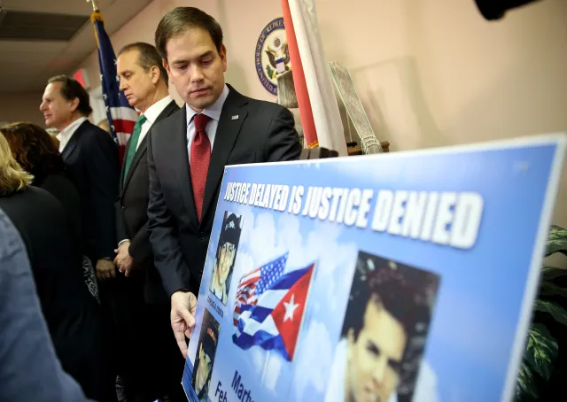 Then-Senator Marco Rubio (R-FL) stands near a poster with pictures of those lost from the group called