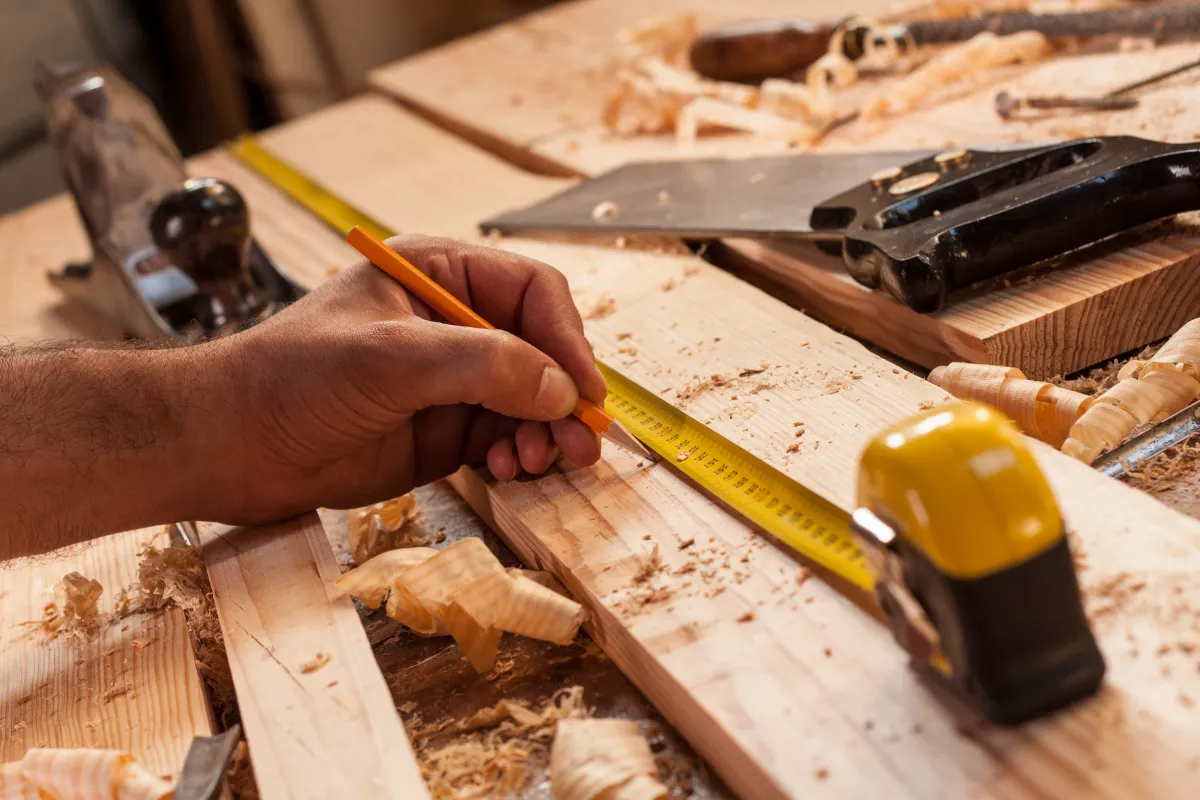 Stock image of a carpenter taking measurement of a wooden plank