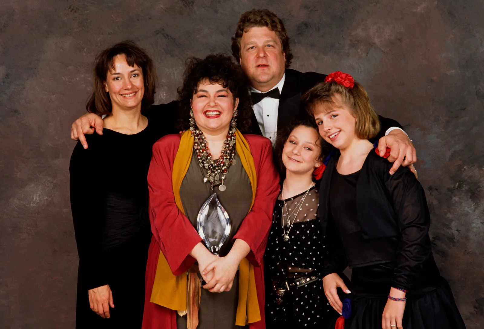BEVERLY HILLS, CA - 1989:  The cast of Roseanne, (l-r) Laurie Metcalf, Roseanne Barr, John Goodman, Sara Gilbert and Lecy Goranson, pose backstage after winning the 1989 People's Choice Award for best TV Comedy in Beverly Hills, California.  (Photo by George Rose/Getty Images)