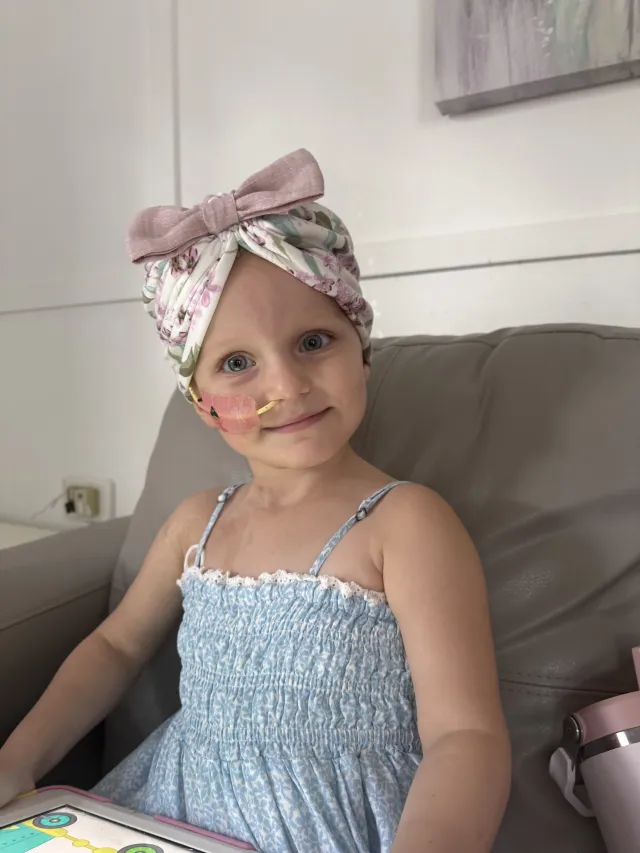 Olivia wears a headscarf and has a feeding tube.