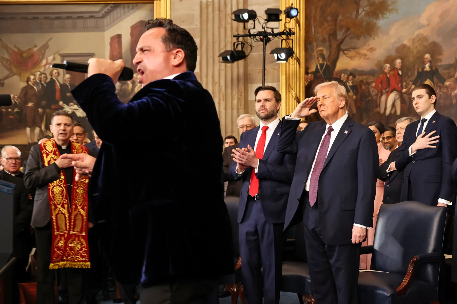 President Donald Trump salutes as opera singer Christopher Macchio performs during the 60th Presidential Inauguration in the Rotunda of the U.S. Capitol in Washington, Monday, January 20, 2025. (Chip Somodevilla/Pool Photo via AP)