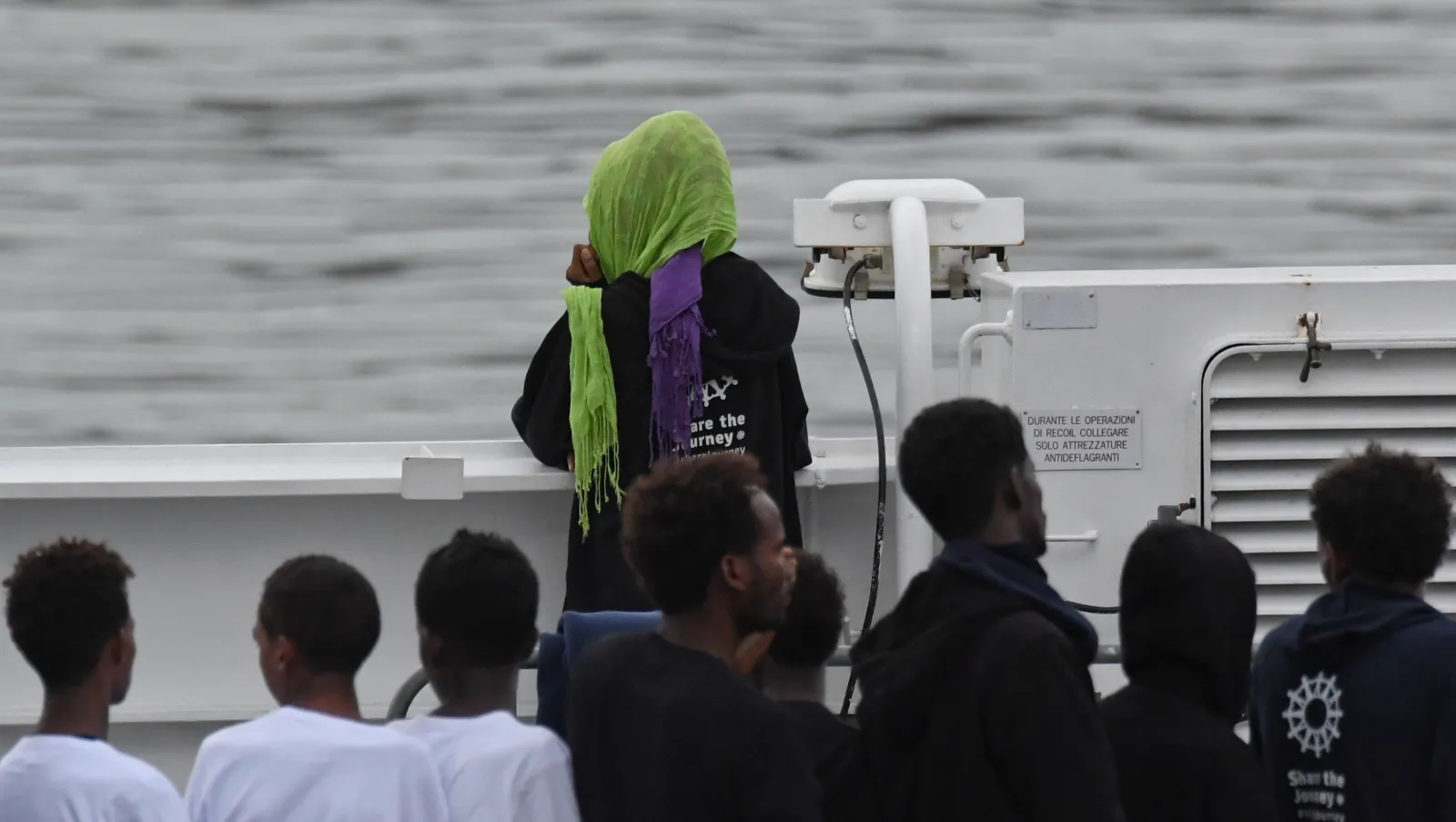 Migrants stand on the deck of the Italian Coast Guard ship Diciotti, moored at the Catania harbor, on August 21, 2018. (AP Photo/Salvatore Cavalli)