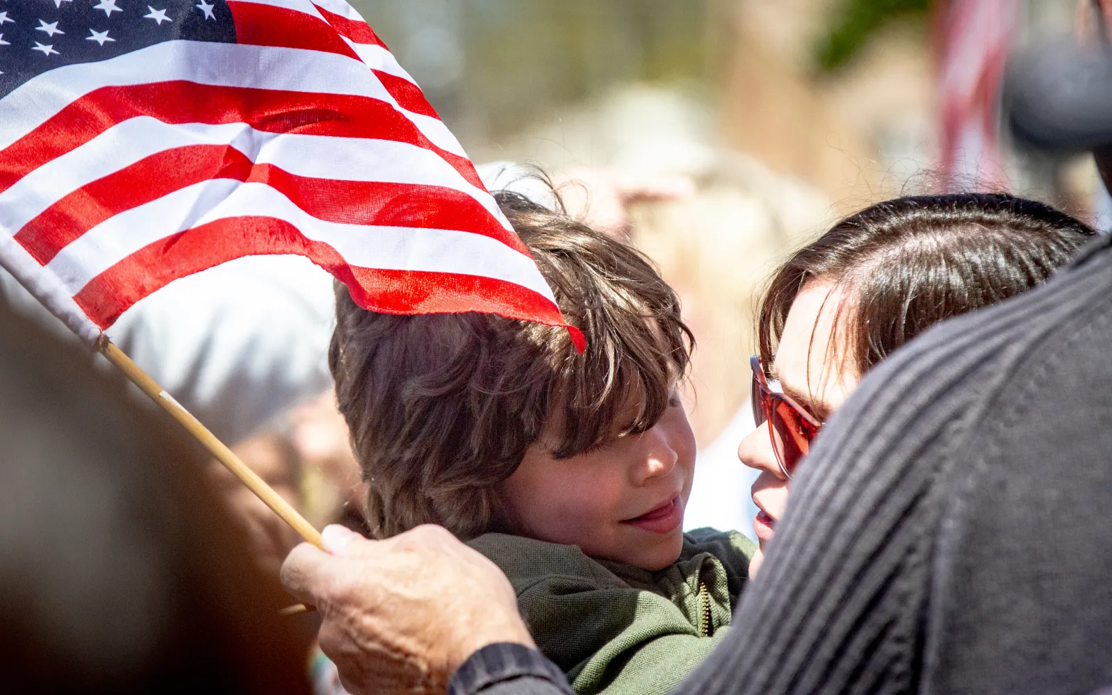 A child is held by his mother as she waves a U.S. flag during the "No Kings" rally at Wilson Park in Florence, Alabama, on March 28, 2026.