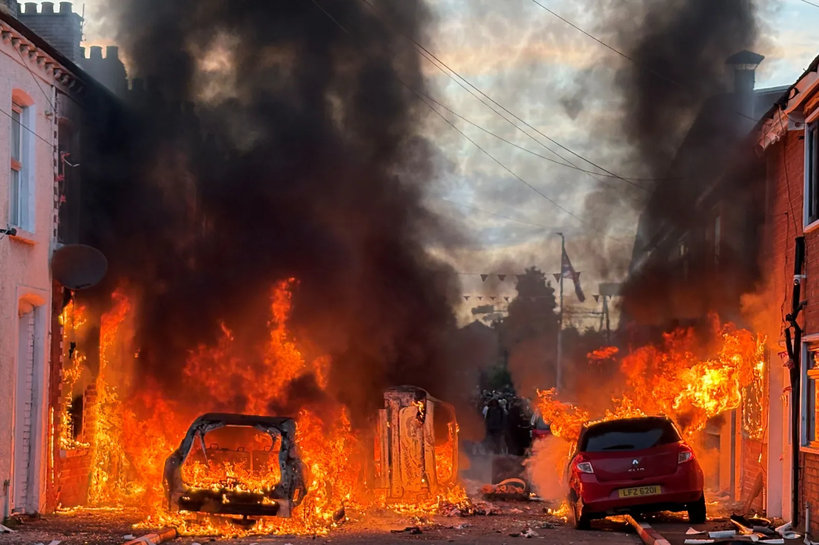 Vehicles set on fire by protesters burn on Lendrick Street in east Belfast, Northern Ireland, on June 9 after the arrest of a Sudanese man accused of stabbing a man in the northern part of the city. (PA via AP)
