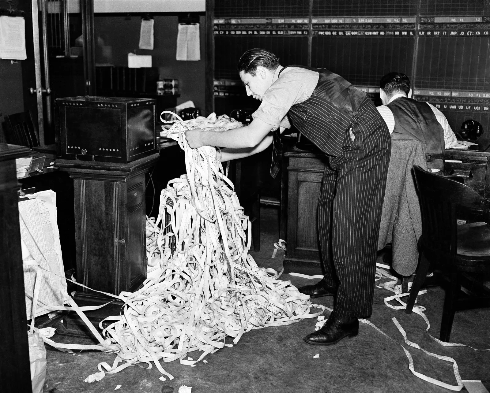 A clerk deals with a mound of ticker tape at the investment house of Merrill, Lynch, Pierce, Fenner and Beane on March 26, 1942. (AP Photo/Bob Wands)