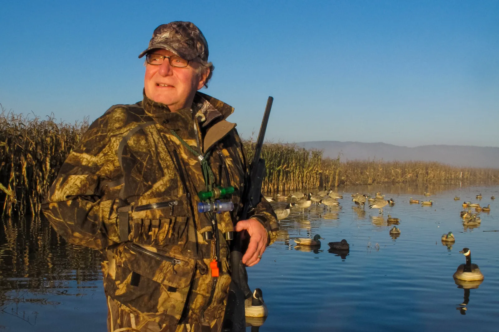 A man in camo gear holds his rifle while duck-hunting near Portland, Oregon, in 2012.