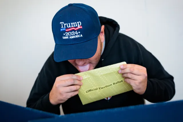Kenny Laureno, 24, seals an official election ballot while voting "On Demand" using an absentee or mail-in ballot on October 15, 2024 in Doylestown, Pennsylvania.