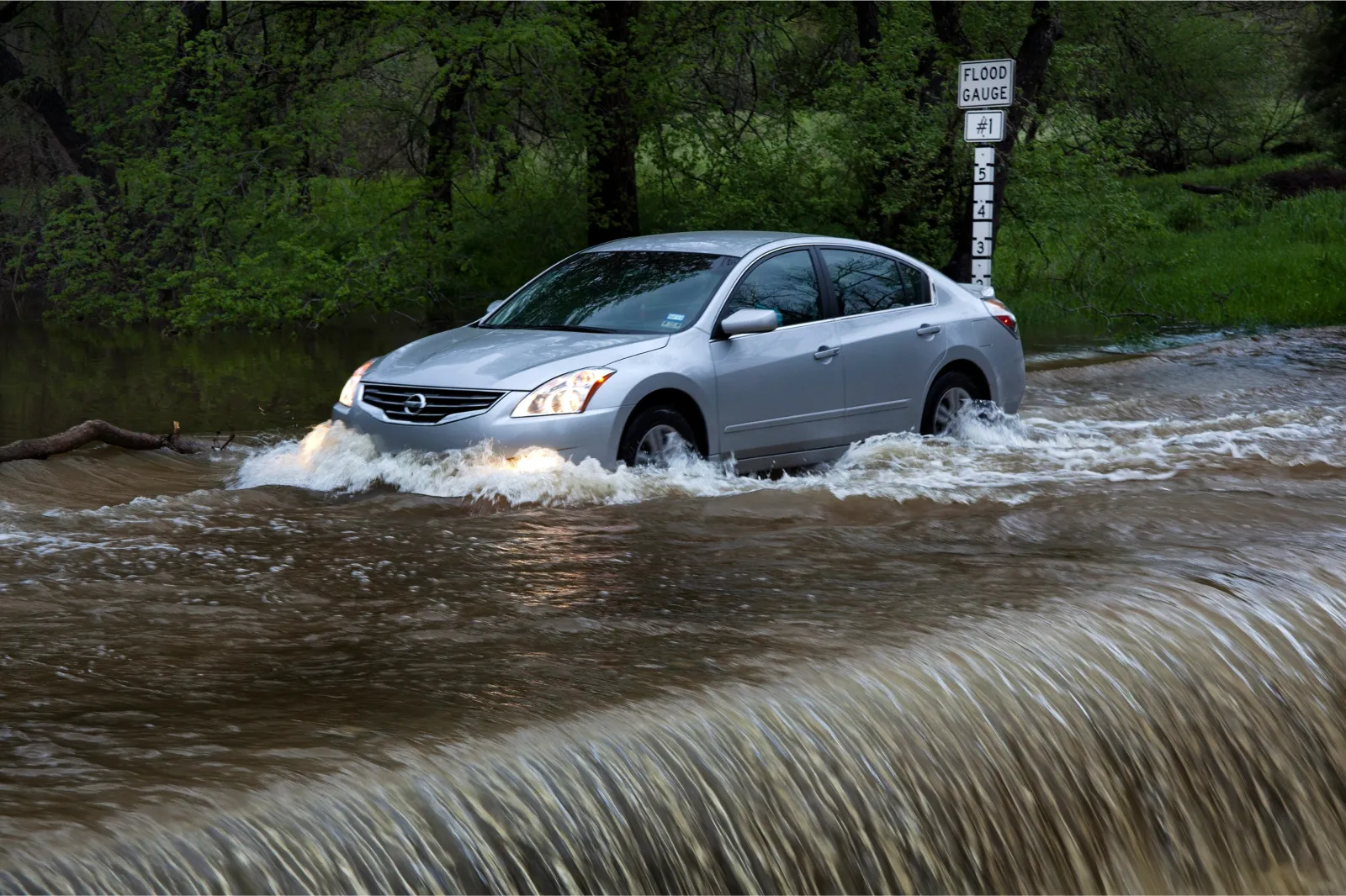 Cars in Austin drive through a flooding Bull Creek filled with face moving water | Getty Images
