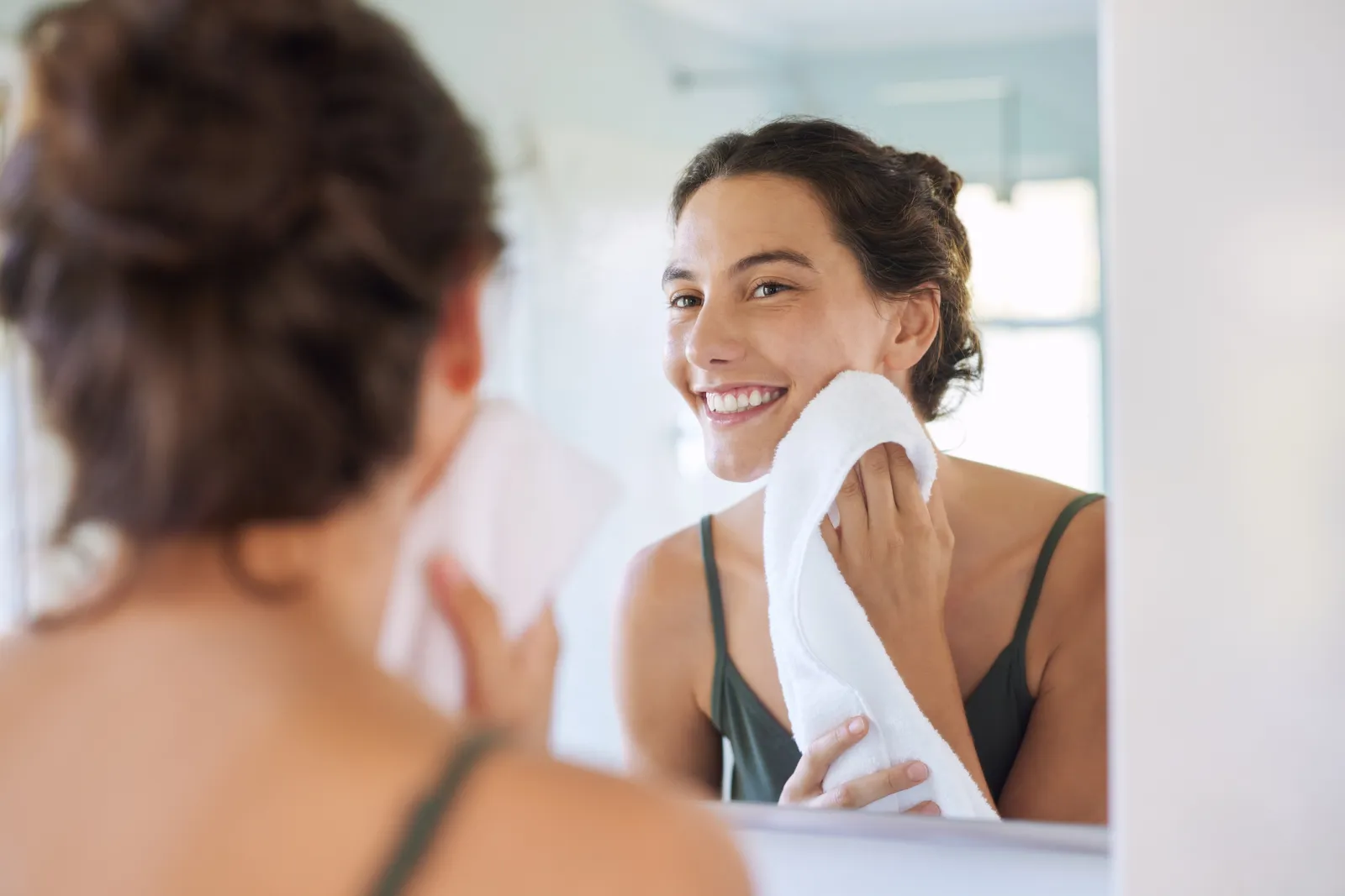 A stock image of a woman drying her face with a towel.