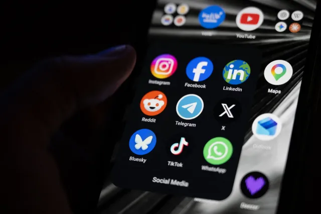Stock image of a smartphone screen displaying the logos of popular social media platforms.