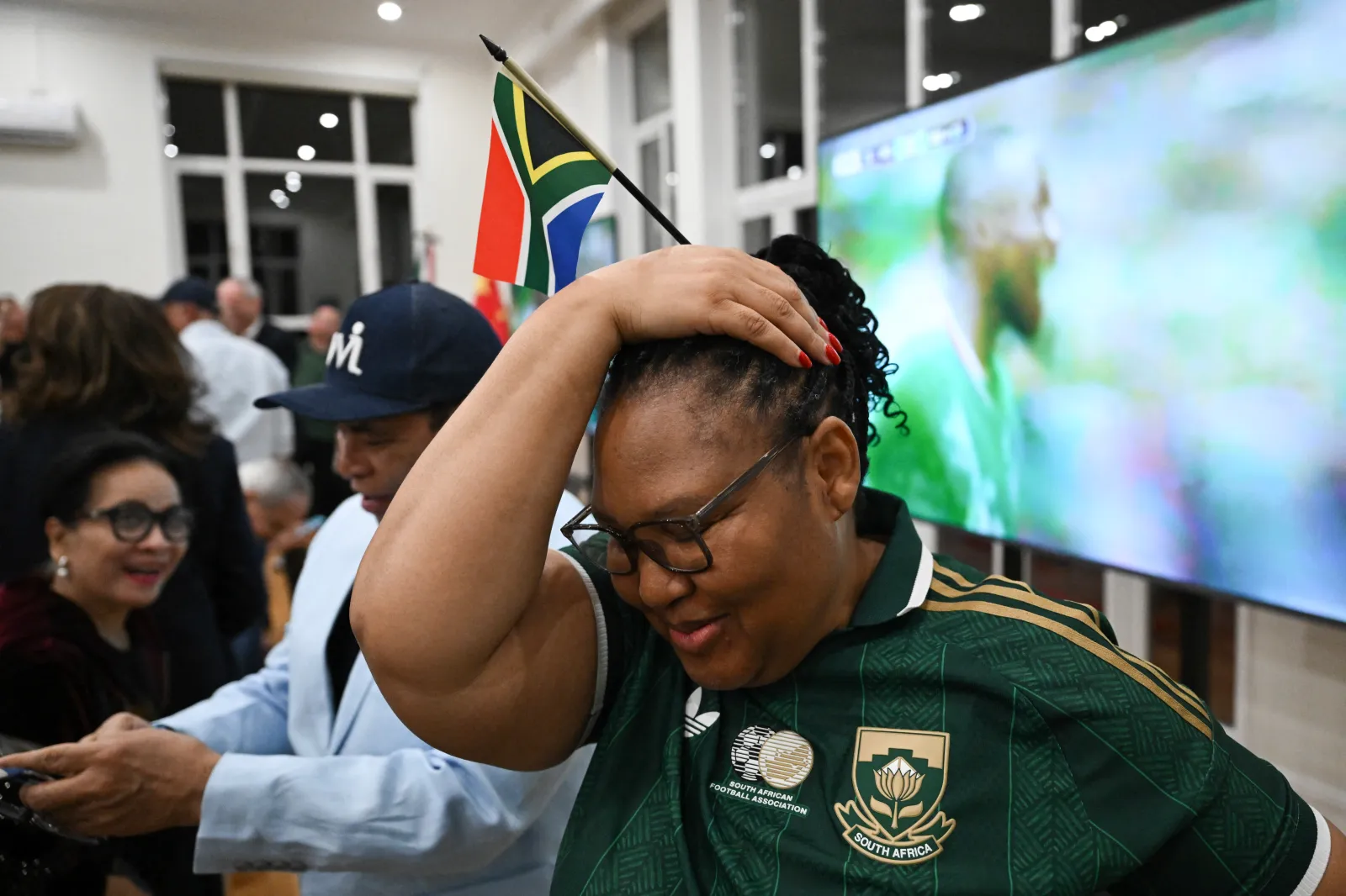 A South African fan reacts after Mexico's first goal as she gathers to watch the live broadcast of the World Cup Group A football match between Mexico and South Africa at the Mexican embassy in Beijing on June 12, 2026. (Photo by Pedro PARDO / AFP via Getty Images)