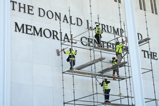 Workers stand on scaffolding near the signage for the Donald J. Trump and John F. Kennedy Memorial Center for the Performing Arts in Washington, DC, on June 12, 2026. A US federal judge on Friday rejected a bid by the board of the Kennedy Center and the Justice Department to halt the removal of President Donald Trump's name from the performing arts venue. District Judge Christopher Cooper, in a ruling last month, ordered Trump's name taken off the iconic building in the nation's capital by Friday, June 12, 2026. (Photo by Alex WROBLEWSKI / AFP via Getty Images)