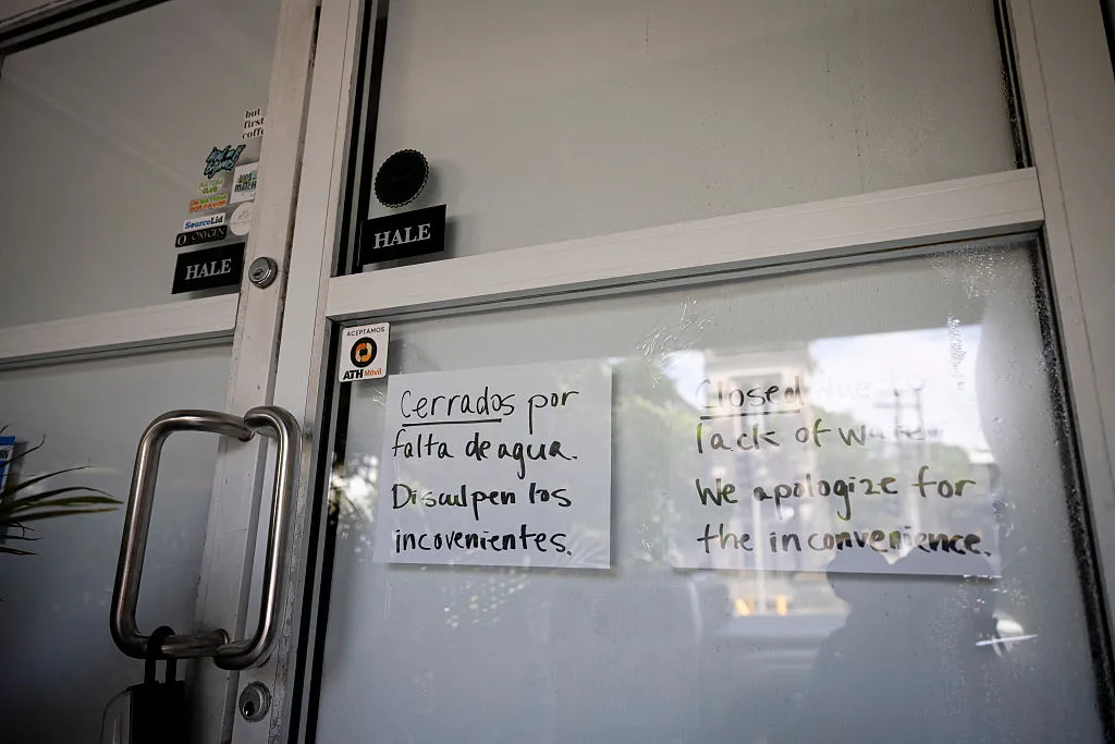 A sign advising customers that the business is closed due to water shortages is displayed in San Juan, Puerto Rico. (Photo by Ricardo ARDUENGO / AFP via Getty Images)