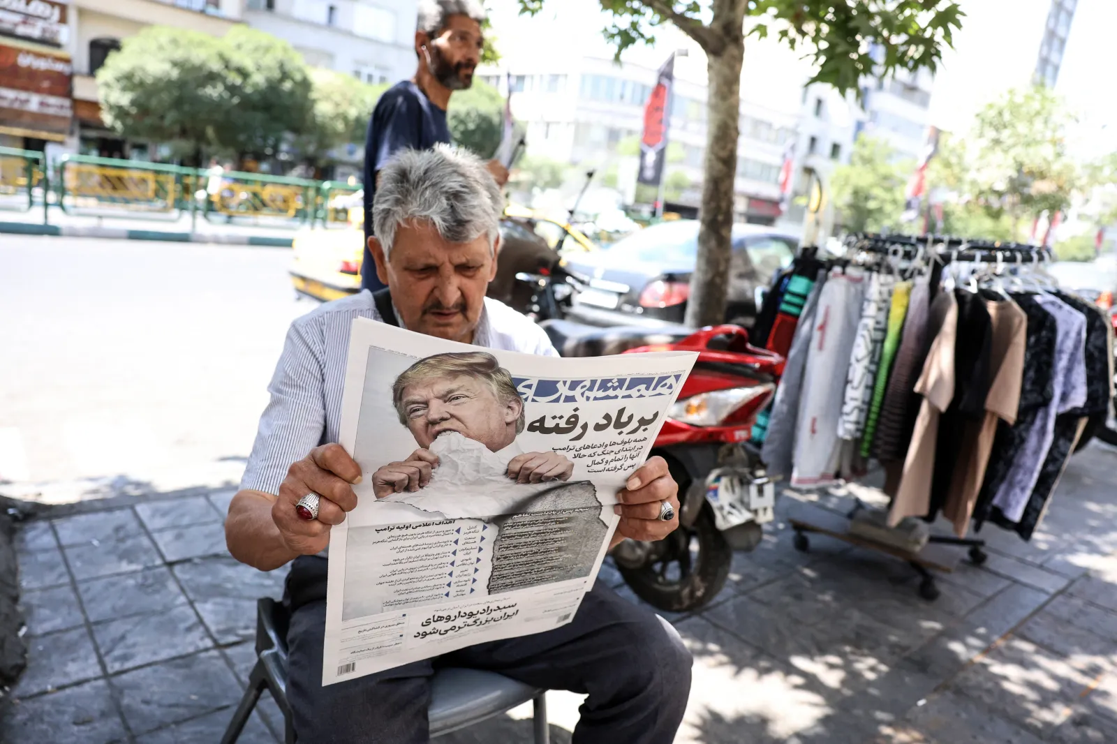 A man reads a newspaper showing President Donald Trump and the headline "Gone with the wind" in Tehran on June 18, 2026.