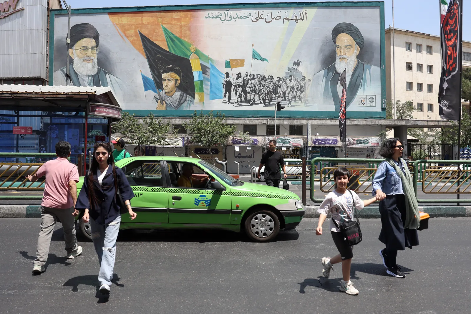 Iranians walk past a mural of Supreme Leaders Ayatollah Ali Khamenei (L) and Ayatollah Ruhollah Khomeini (R) in Tehran on June 18, 2026.