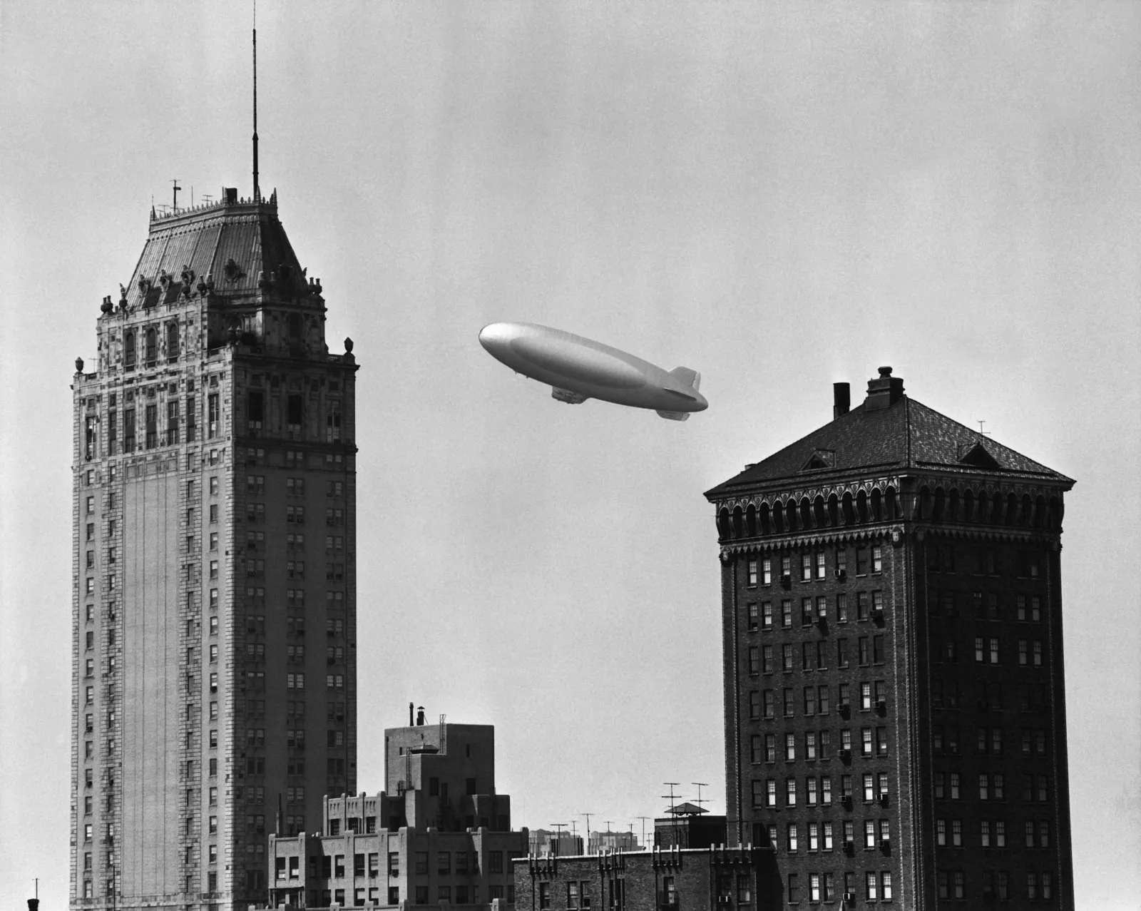 A blimp pictured flying over a city circa 1950.