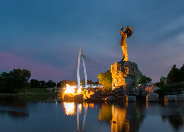 Lighting of the flames at the Keeper of the Plains steel sculpture on the Arkansas River in Wichita, Kansas.