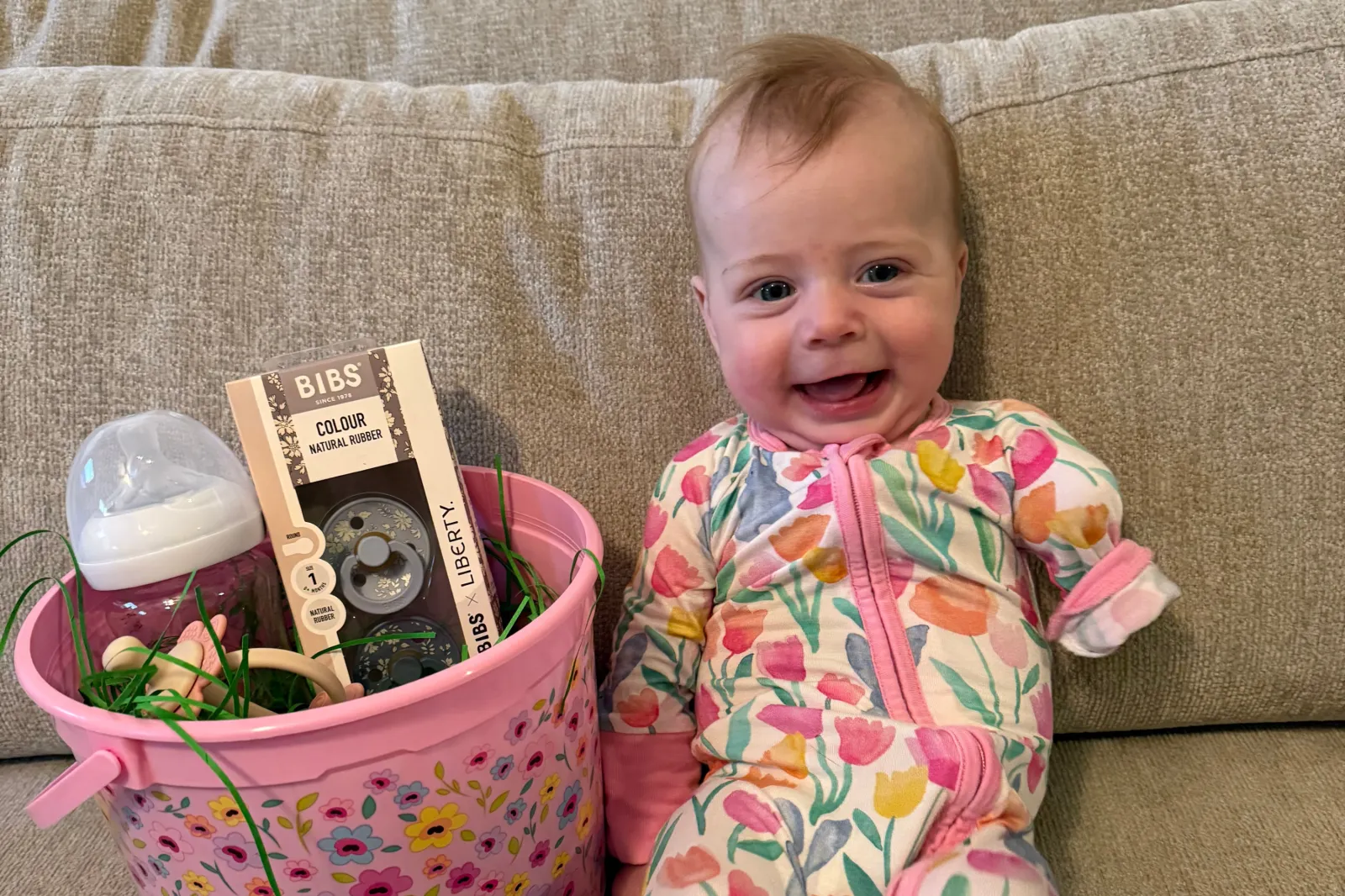 Holland, now 7 months old, smiles as she sits on a couch.