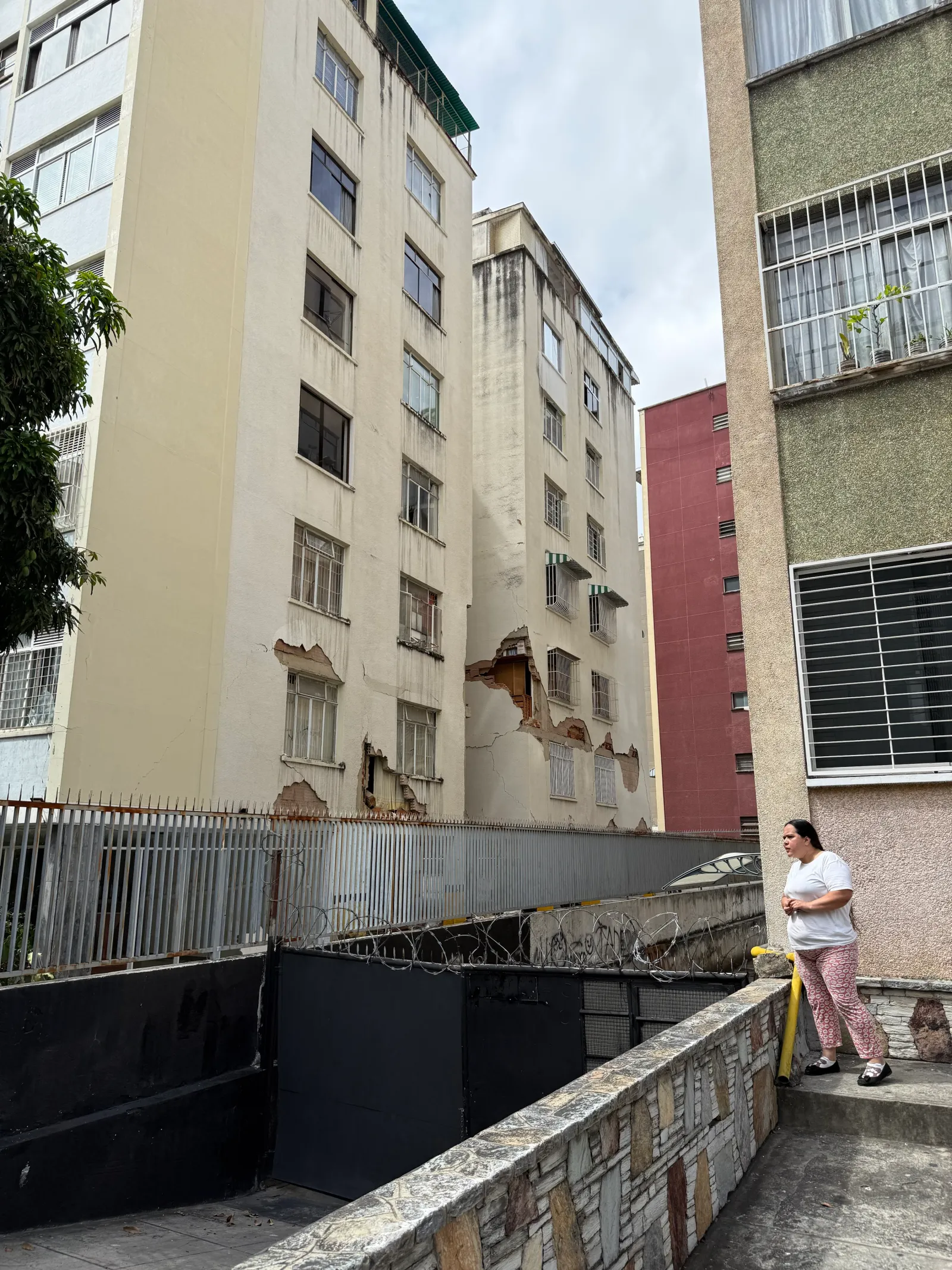 Caracas'ta bir sakin, depremlerin yol açtığı yıkımın boyutunu gösteren büyük çatlaklar ve sıva dökülmelerinin olduğu hasarlı bir apartman binasına bakıyor.