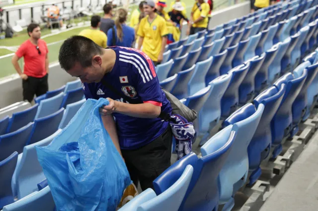 A Japan fan helps collect litter from the stadium after the 2014 FIFA World Cup Brazil Group C match between Japan and Colombia at Arena Pantanal on June 24, 2014 in Cuiaba, Brazil.
