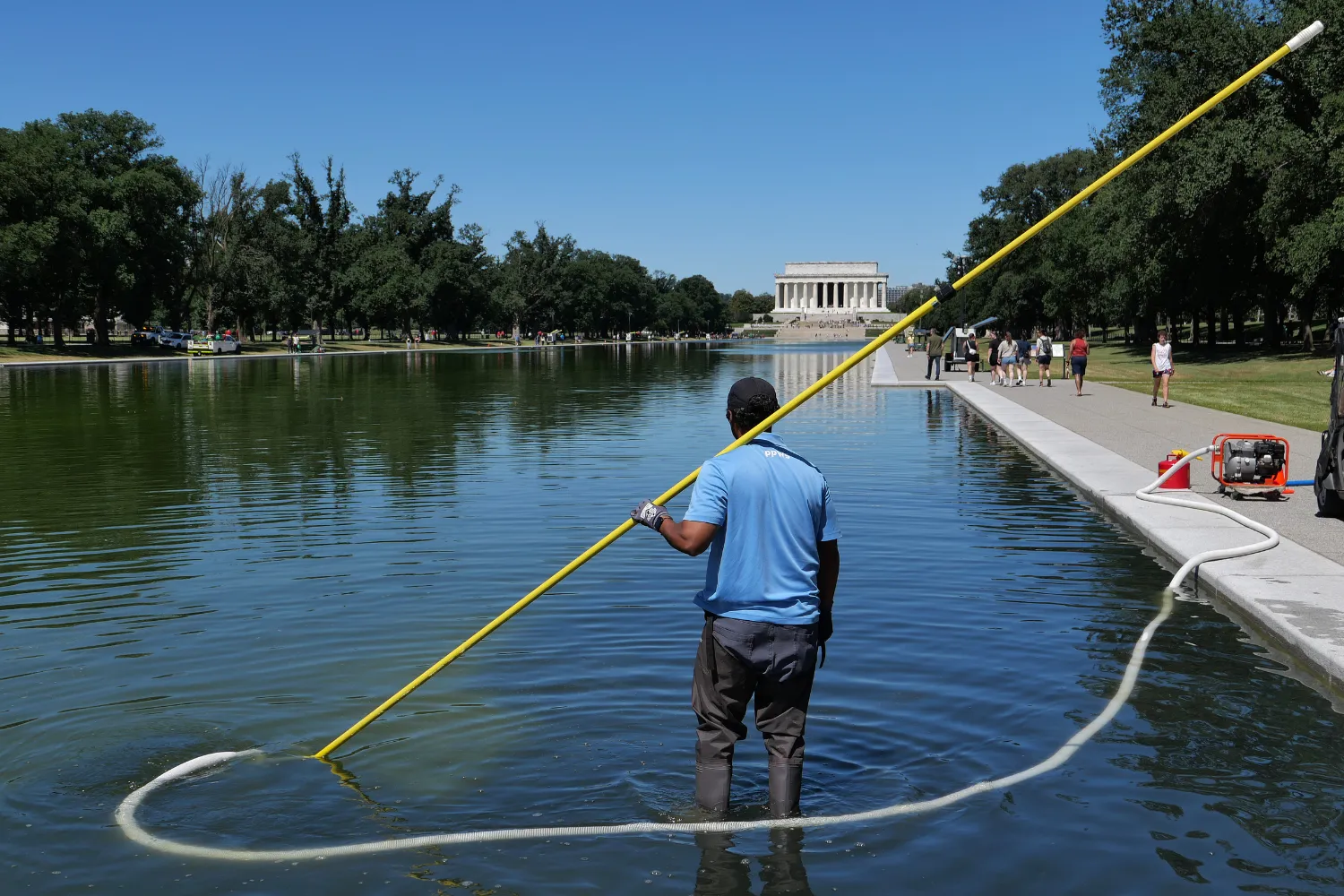 A U.S. National Park Service employee uses a vacuum pump to clean algae off the bottom of the newly repainted Lincoln Memorial Reflecting Pool on the National Mall on June 16, 2026 in Washington, D.C.