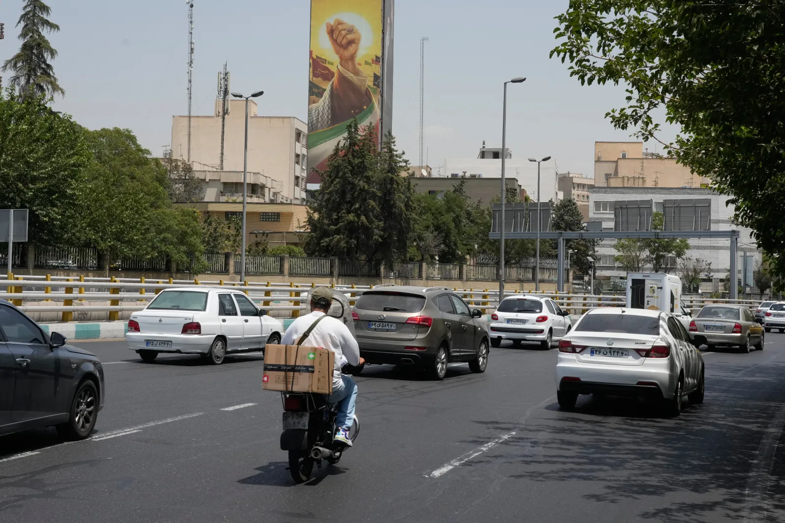 Vehicles drive past a billboard depicting the clenched fist of the late Iranian Supreme Leader Ayatollah Ali Khamenei, in Tehran, Iran, on July 21, 2026.