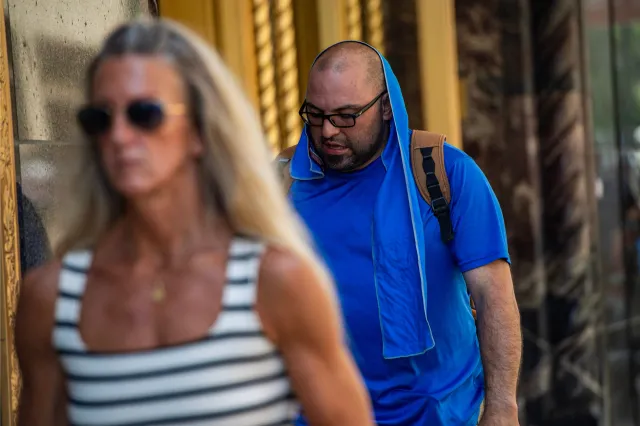 A man walks with a towel draped over his head and neck during a heat wave in Boston, Massachusetts on July 1, 2026. | Getty Images