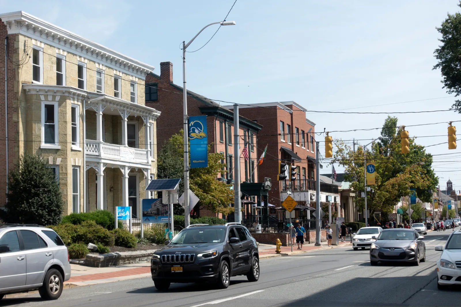 Stock image: traffic passes the main street with people walking on a sidewalk in Newark in 2019.