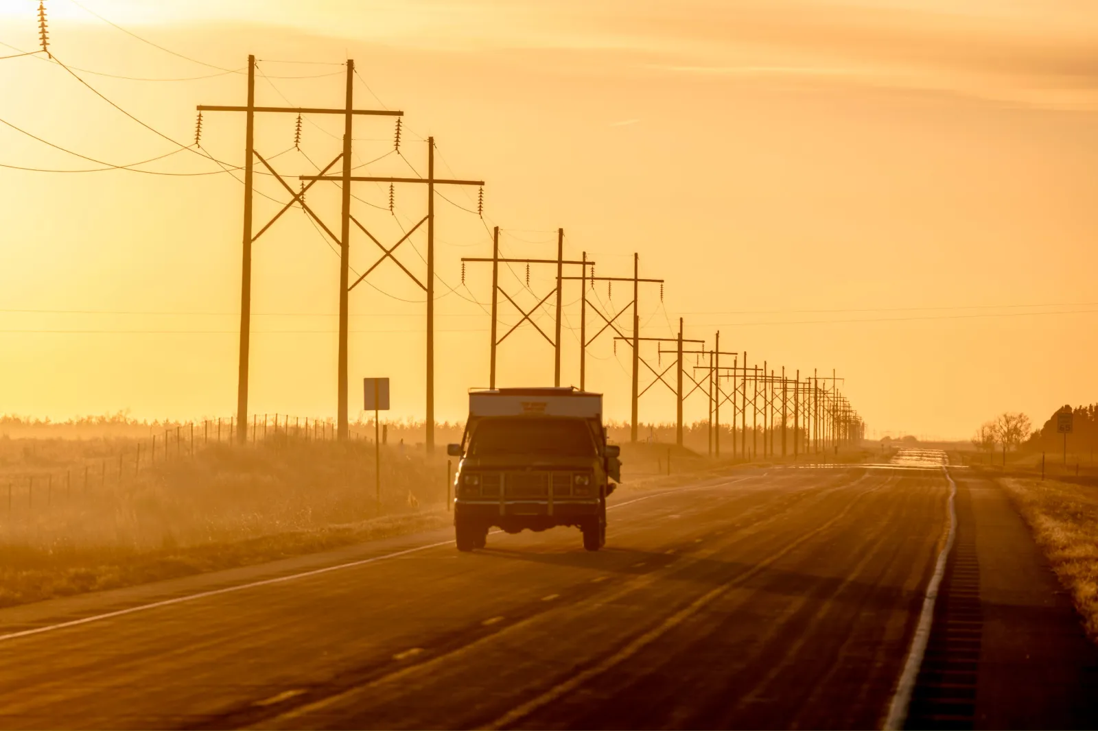 File image: A sunset is seen with a pickup truck driving by a row of power lines