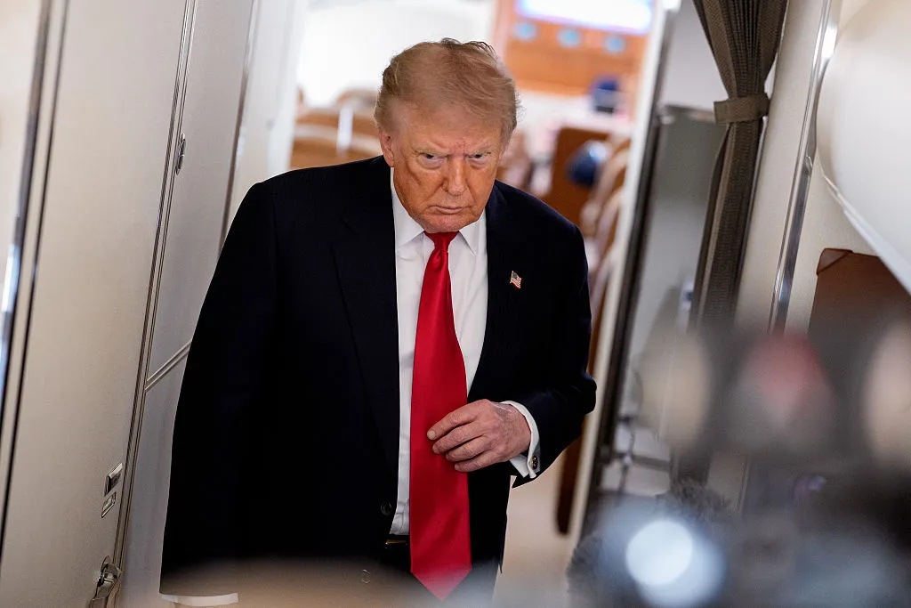 President Donald Trump walks towards members of the media to speak while aboard Air Force One for a trip to Michigan on July 27 in flight. (Photo by Andrew Harnik/Getty Images)