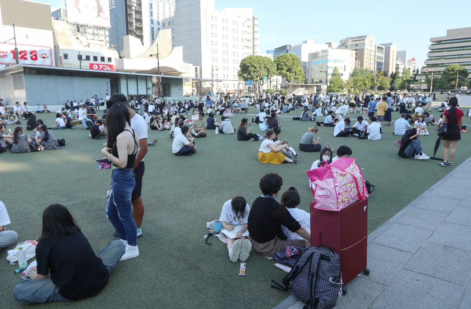 People wait in a park after evacuating buildings following a strong earthquake in Kumamoto City, Chuo Ward on July 28, 2026, with broadcaster NHK saying that at least 50 people were taken to hospital. (Photo by JIJI Press / AFP via Getty Images)