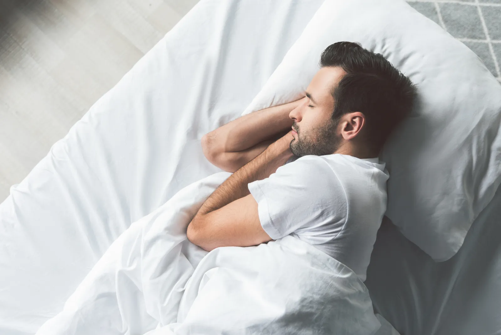 Man sleeping on his side on a bed.