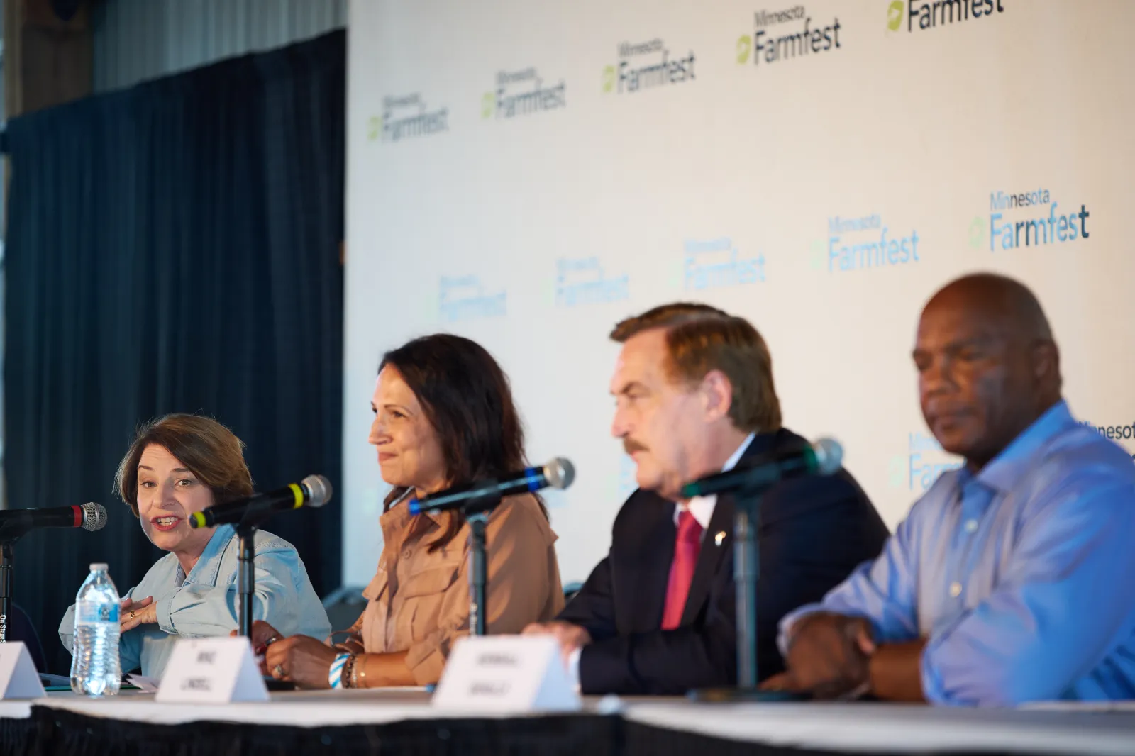 Sen. Amy Klobuchar, D-Minn., left, a candidate for Minnesota governor, speaks during a forum of the gubernatorial candidates while her opponents look on at Farmfest. Wednesday, Aug. 5, 2026, in Morgan, Minn. (AP Photo/Ellen Schmidt)