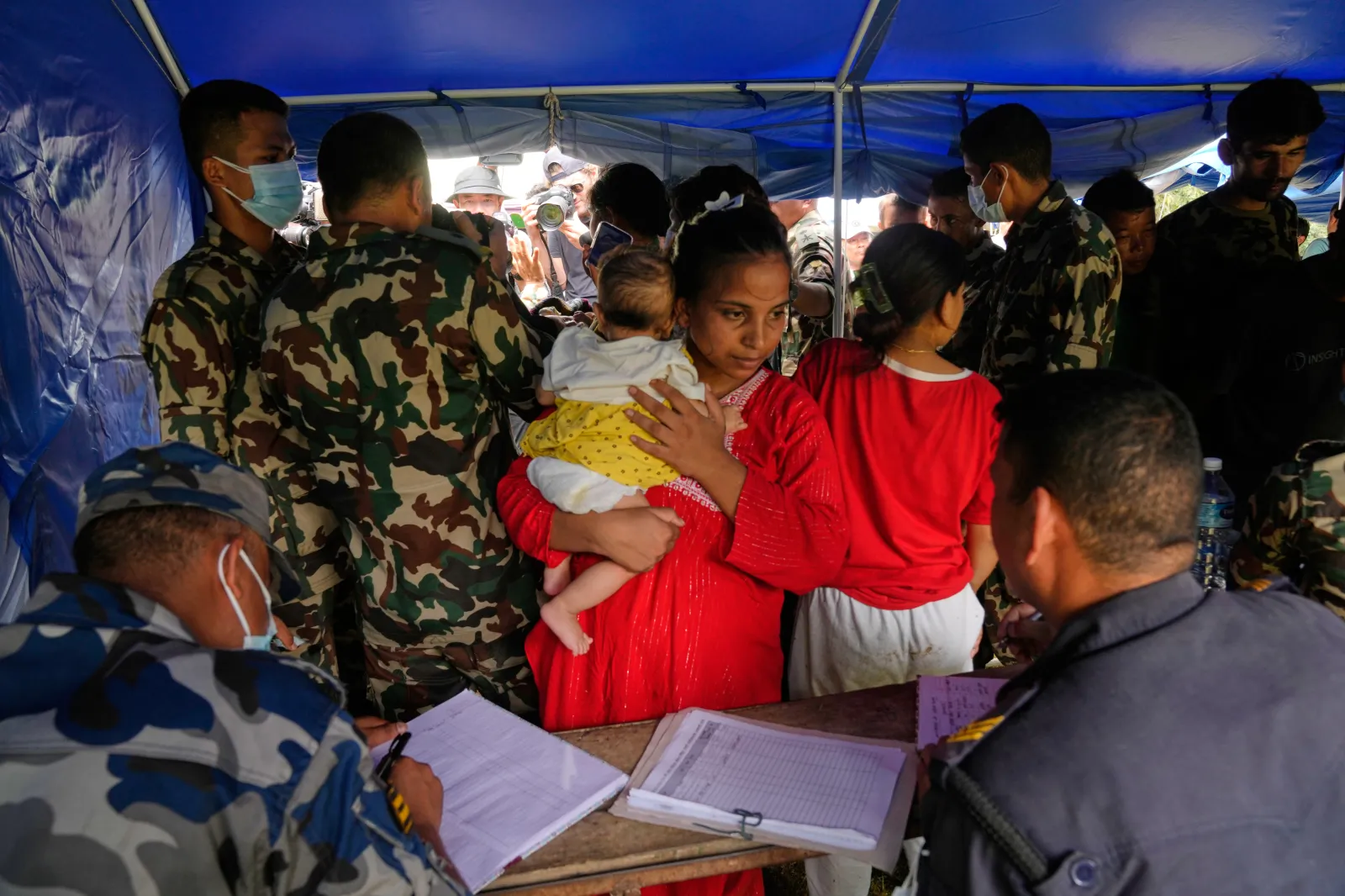 A woman and her child rescued from an area cut off by flash flooding stands for registration in Nepal's Nuwakot district on August 29. (AP Photo/Dar Yasin)