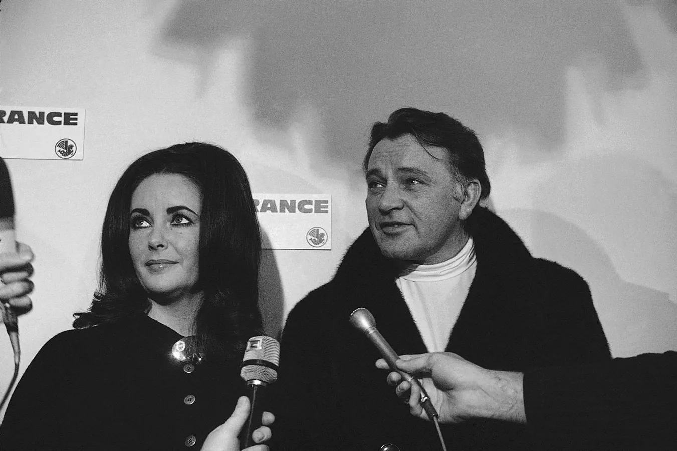 Elizabeth Taylor and her husband Richard Burton talk to newsmen briefly before boarding an Air France plane for Paris at Los Angeles International Airport at night on Nov. 26, 1968.