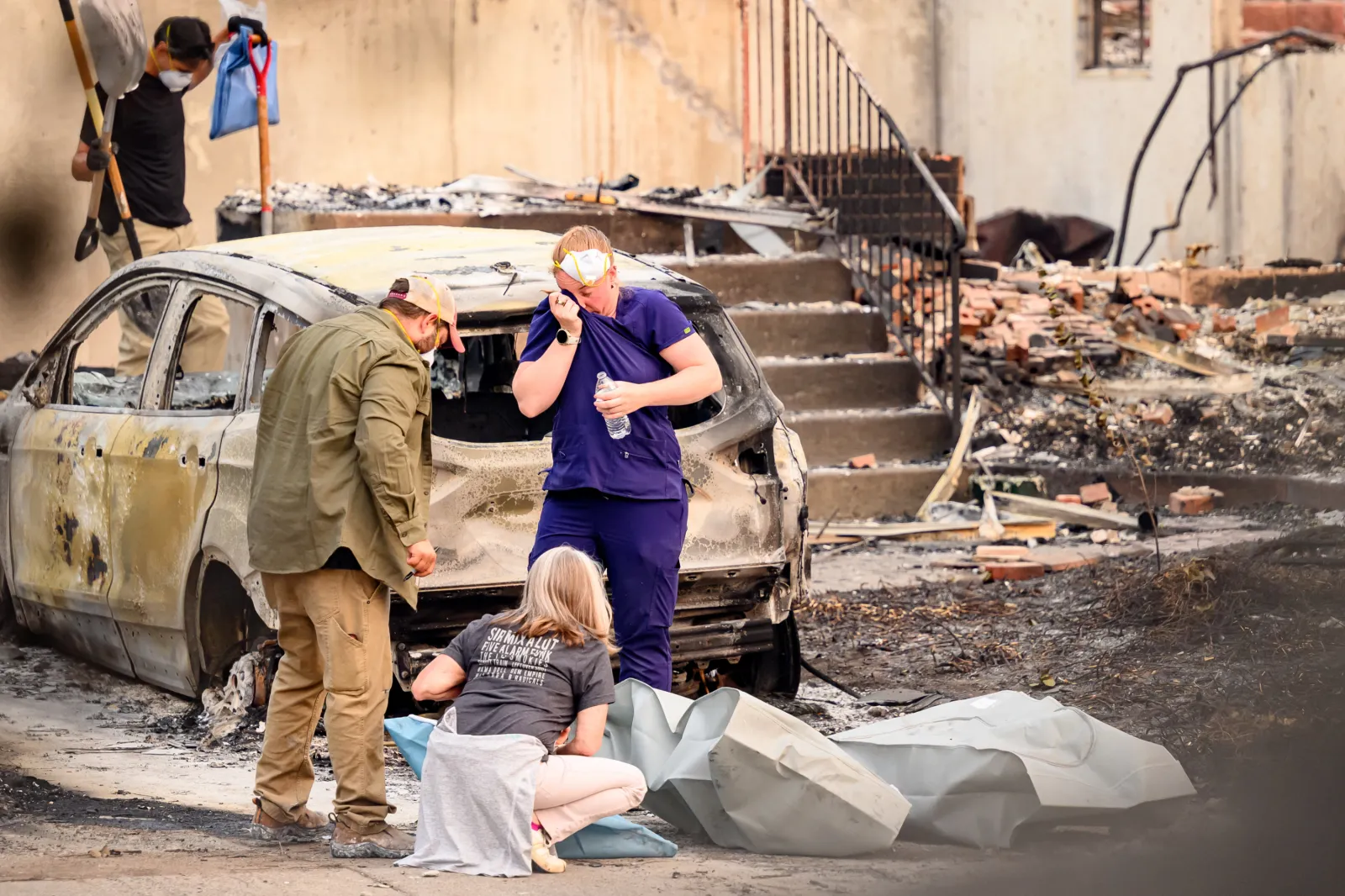 Residents mourn as they place the remains of deceased dogs into body bags at a burned home in Spokane, Washington on August 4, 2026.