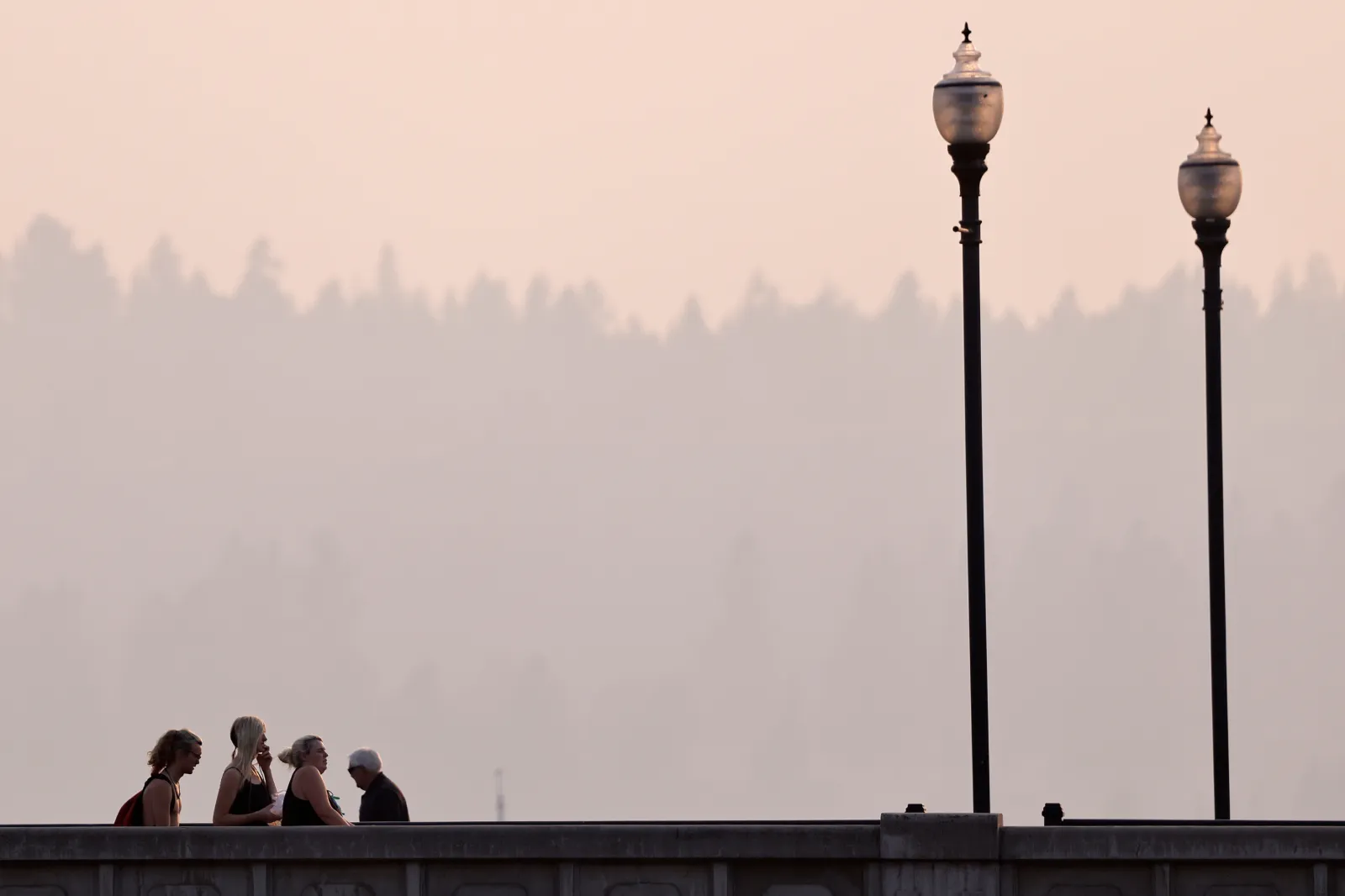 People walk across a downtown bridge amid poor air quality due to wildfire smoke August 6, 2026 in Spokane, Washington