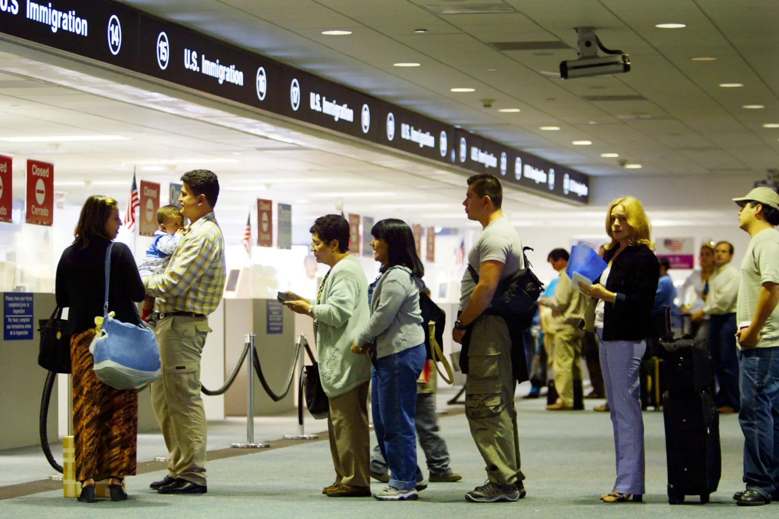 People wait in line to have their passports checked by Immigration inspectors July 2, 2002 at Miami International Airport in Miami, Forida.