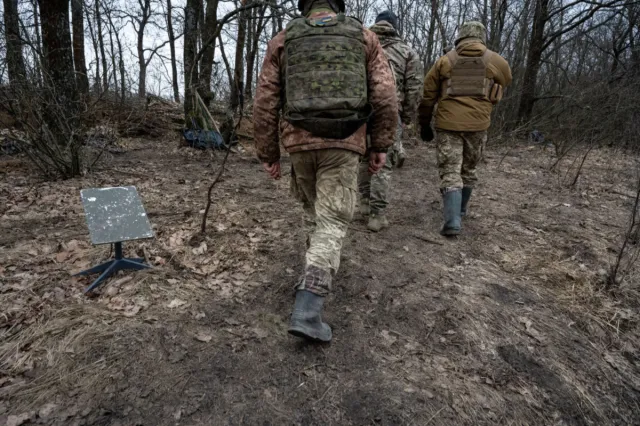 Soldiers of the Ukraine Army's 95th Brigade walk past a Starlink satellite internet receiver on February 18, 2024, in an undisclosed location in Ukraine.