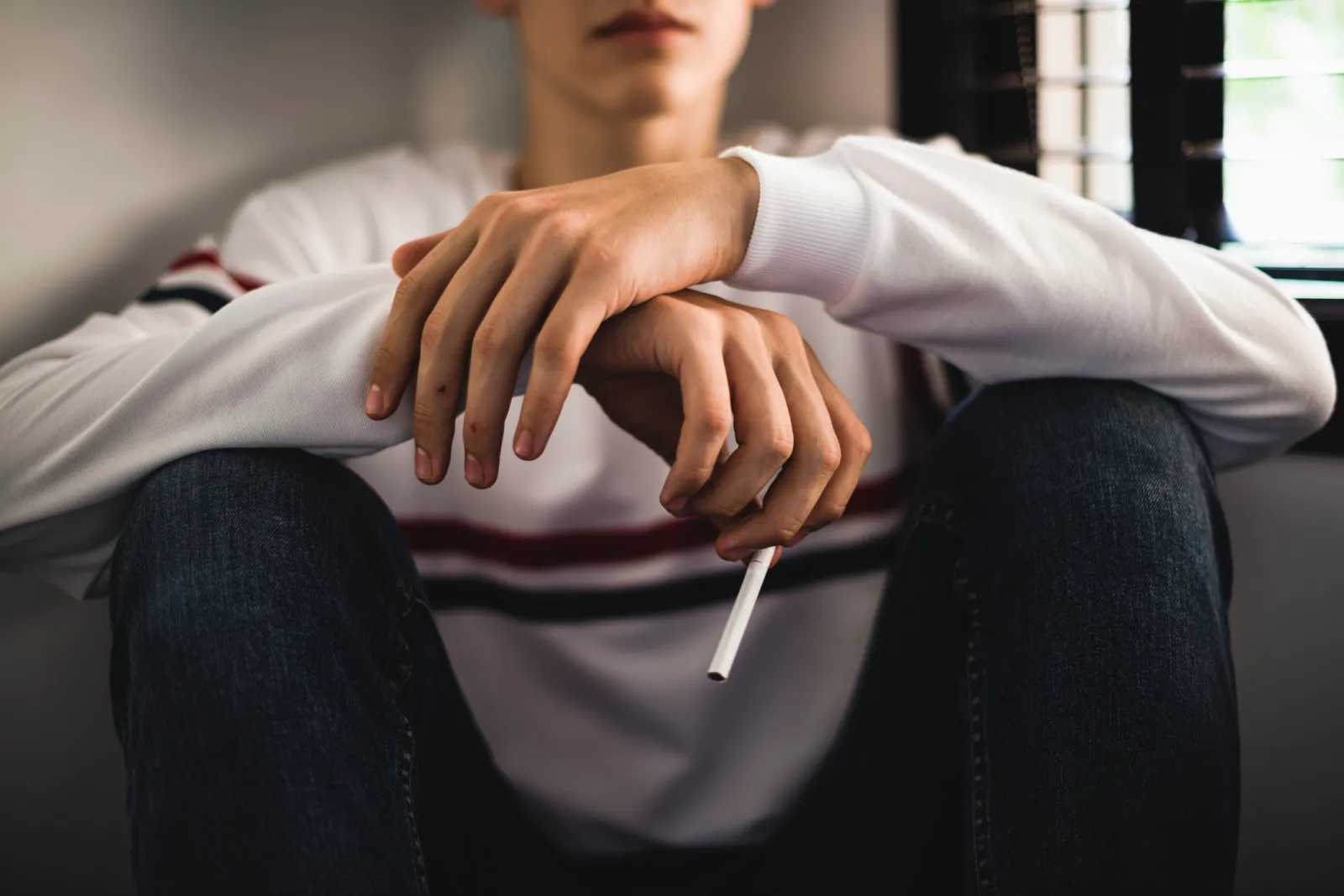A stock image of a young teen holding a cigarette.