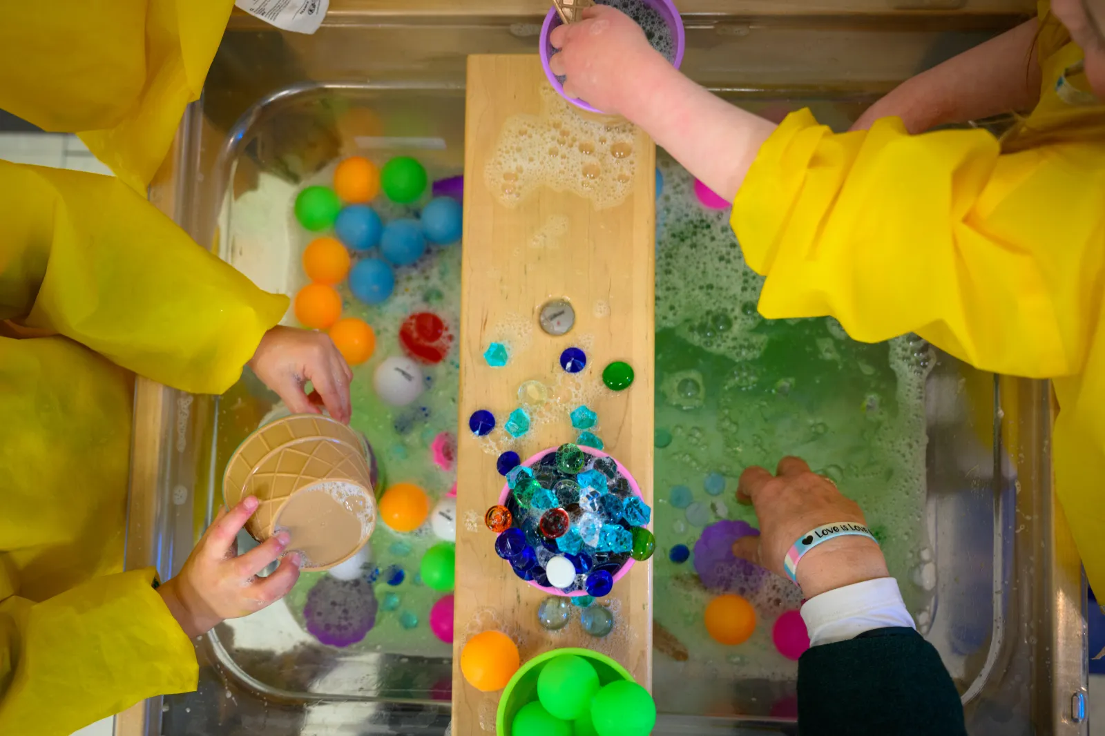 Students play with toys in a basin of soapy water at the Connecticut State University Early Learning Center on March 12, 2025.