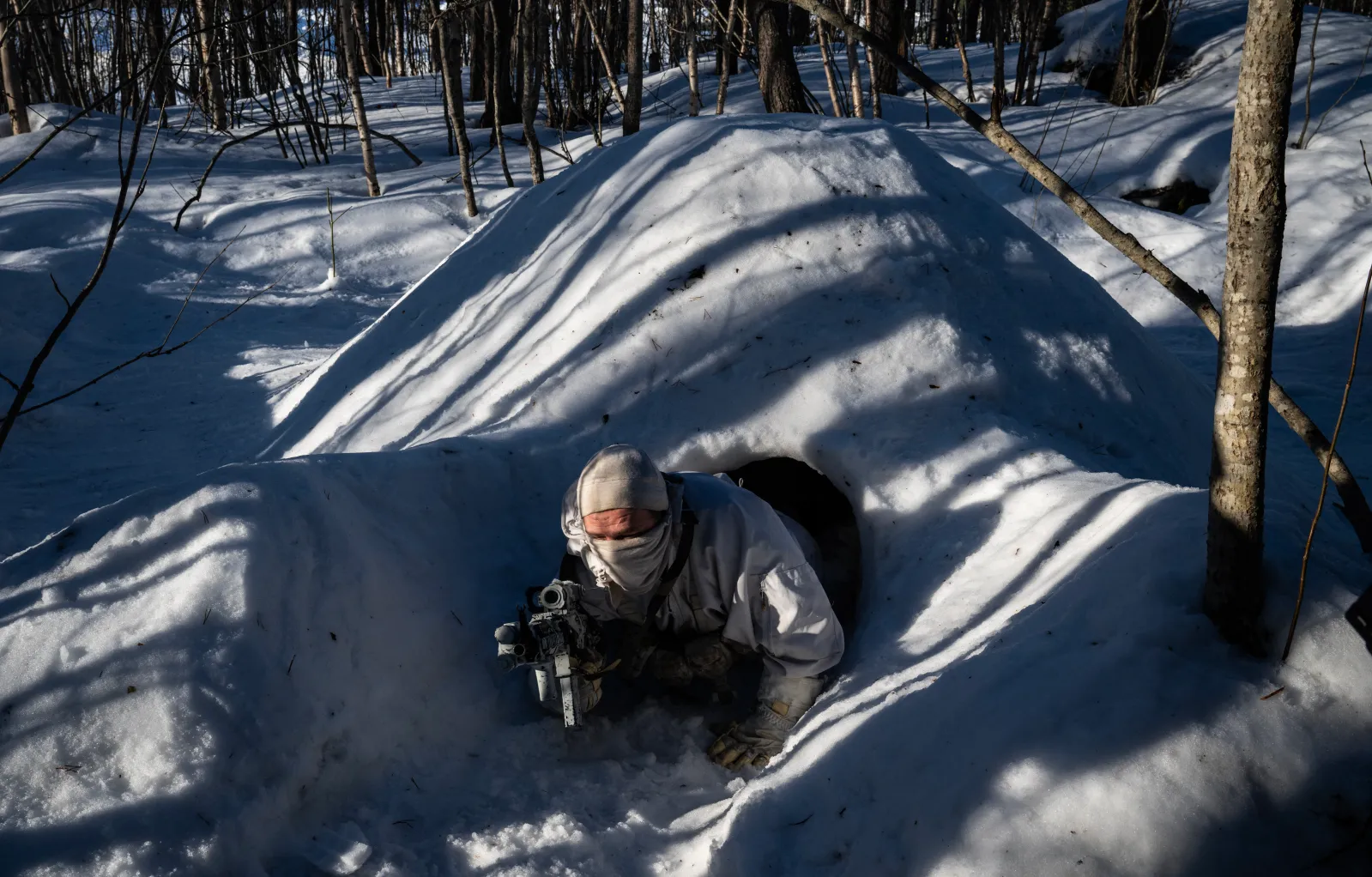 A member of Norway's Military Intelligence Regiment, Long Range Reconnaissance, exits a quinzee (a temporary, dome-shaped snow shelter) during a demonstration near Setermoen in Norway on March 12, 2026, during NATO's Cold Response military exercise.
