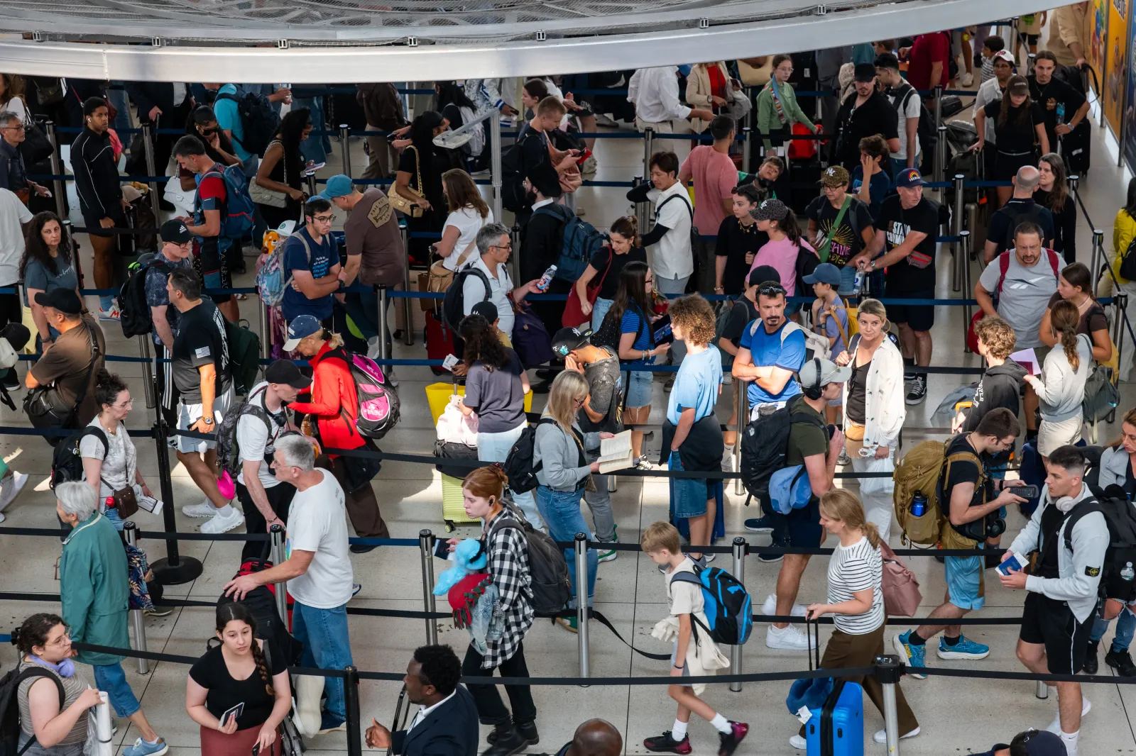 Travelers wait in a security line at John F. Kennedy International Airport in New York City on August 12, 2026.