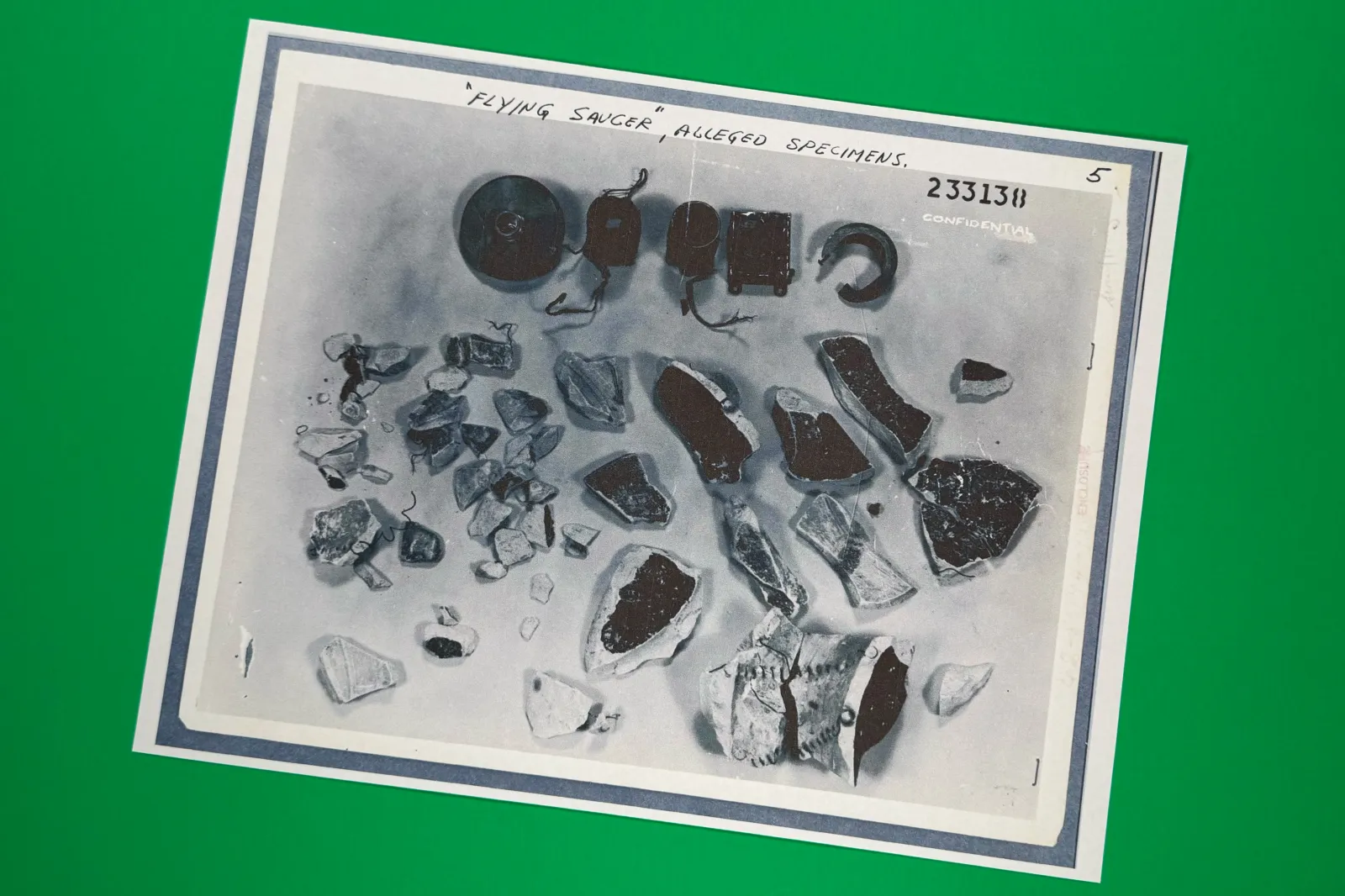 A photo of "flying saucer alleged specimens" in files on UFOs, released May 8, 2026, by the Pentagon, is photographed in Washington. | AP Photo/Jon Elswick, File